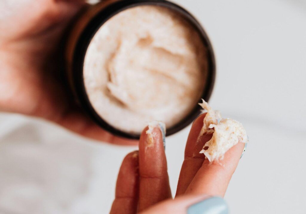 Hands applying skincare cream from a jar, perfect for beauty and cosmetics themes.